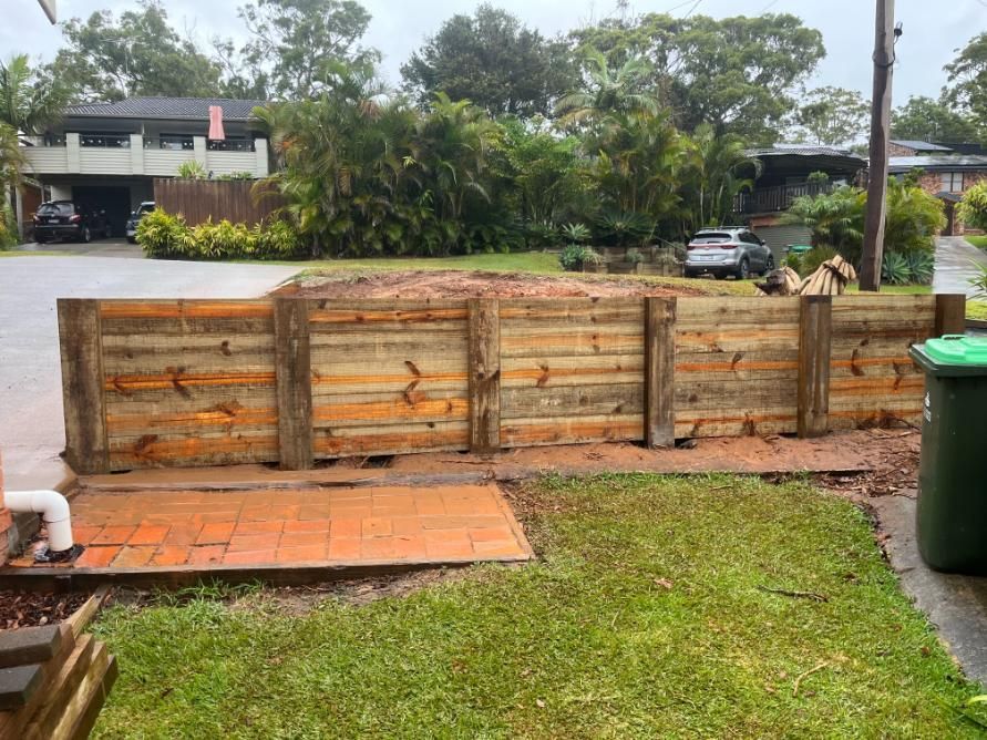 A Wooden Fence Is Being Built In The Backyard Of A House — Lewis Landscapes In Laurieton