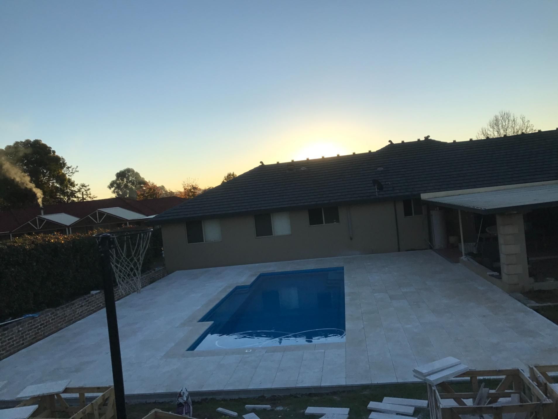 A Large Swimming Pool In Front Of A House At Sunset — Lewis Landscapes In Yippin Creek, NSW