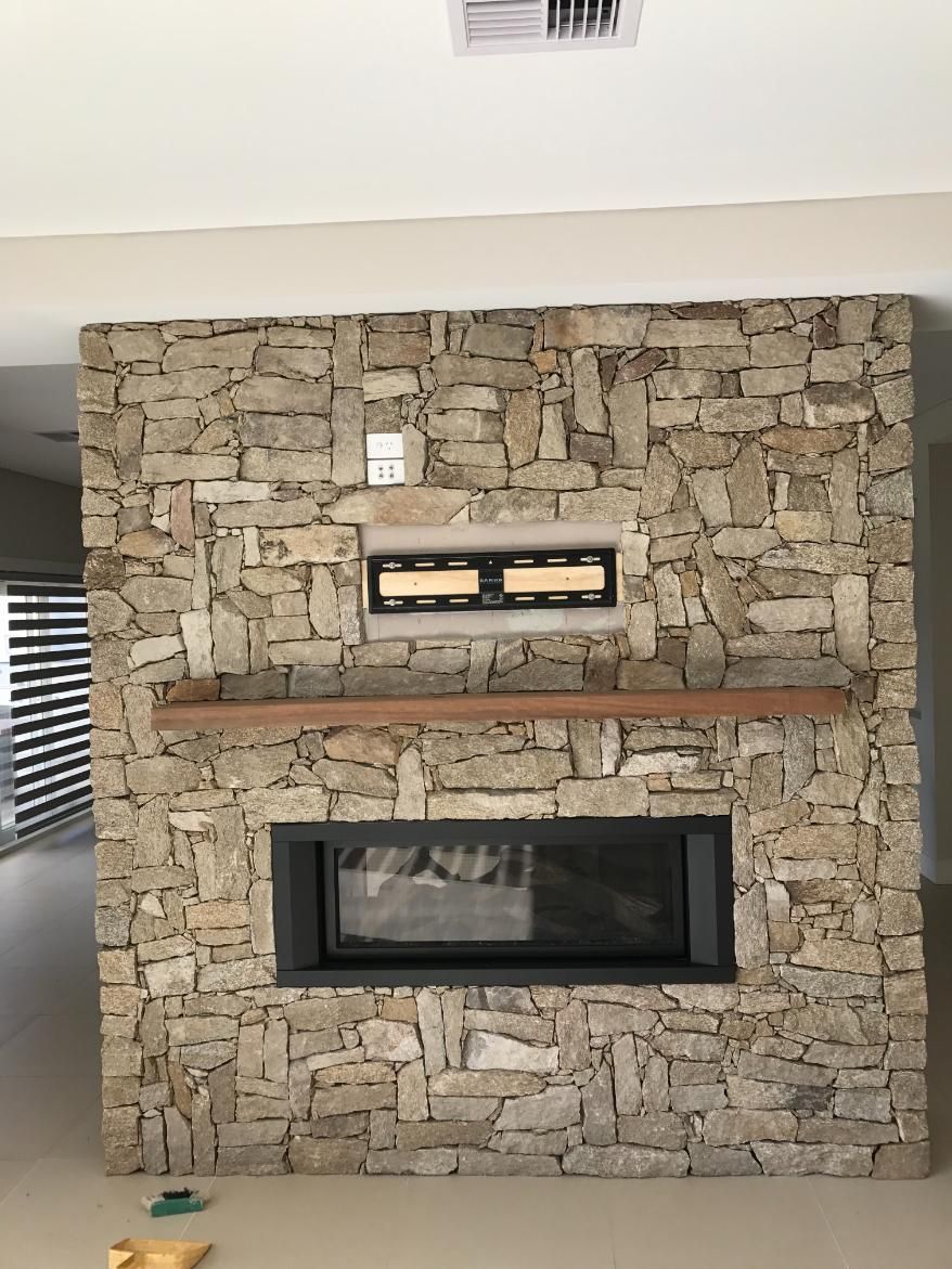 A Large Stone Fireplace With A Wooden Mantle In A Living Room — Lewis Landscapes In Wauchope, NSW