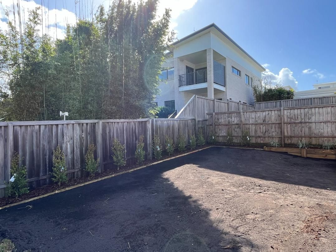 A Large White House With A Wooden Fence Around It — Lewis Landscapes In Laurieton