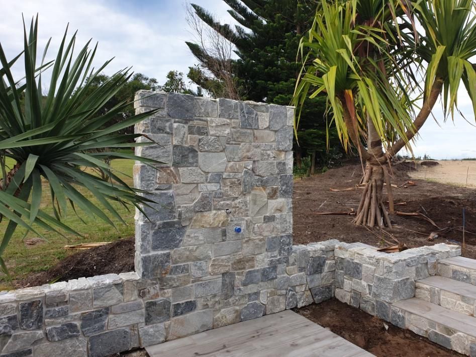 A Stone Wall With A Palm Tree In The Background — Lewis Landscapes In Yippin Creek, NSW
