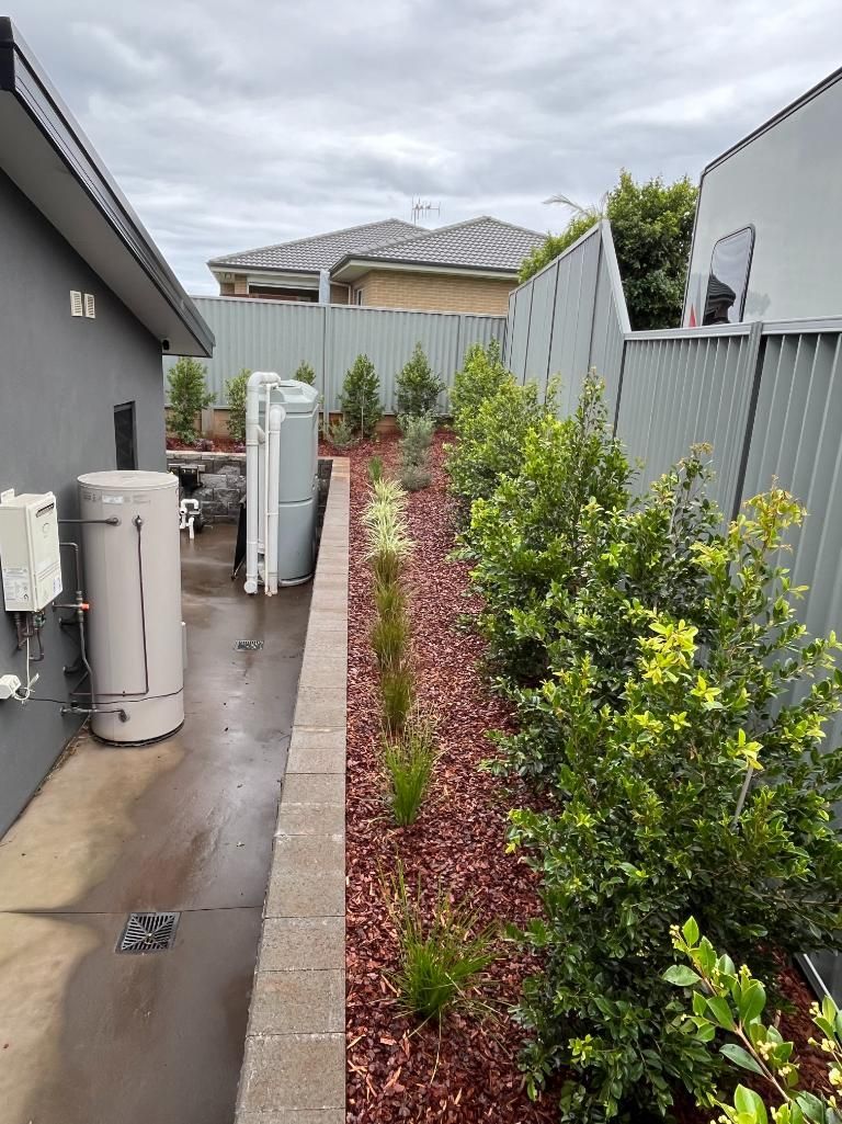 A Sidewalk Leading To A House With A Water Heater And A Fence — Lewis Landscapes In Port Macquarie, NSW