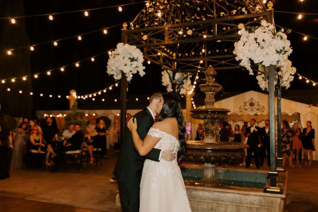 a bride and groom kiss in front of a fountain