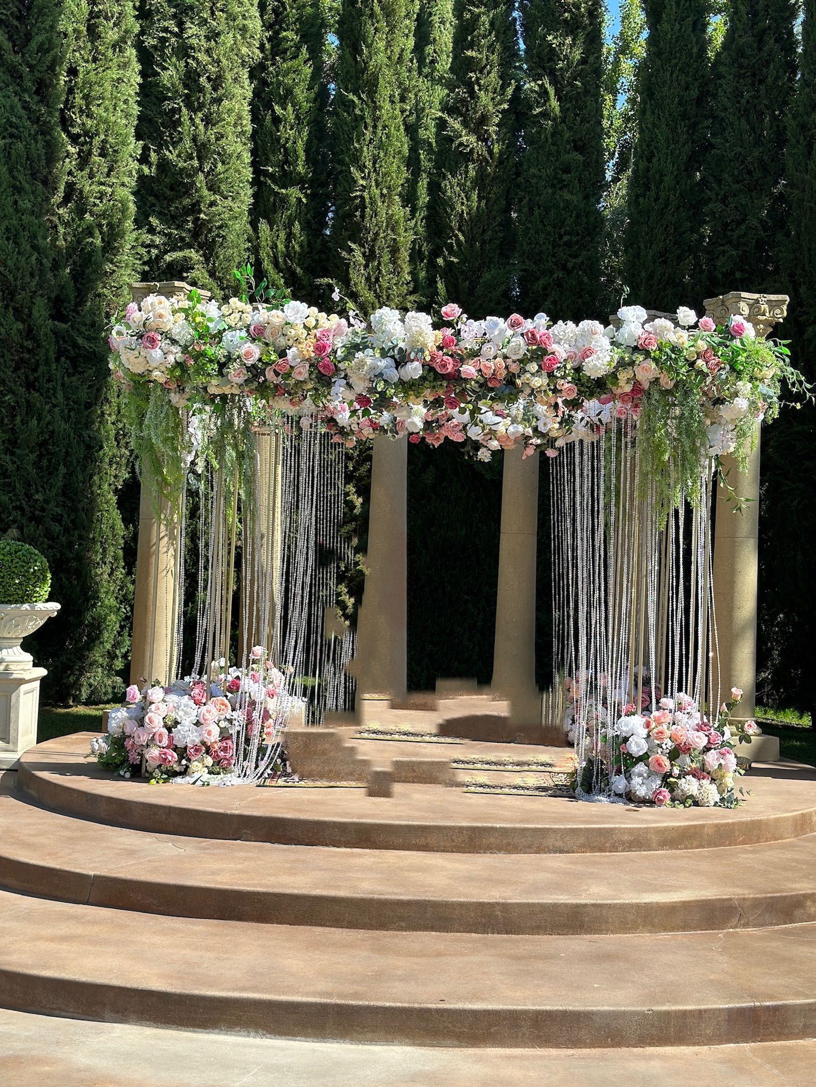 a wedding arch with pink and white flowers and crystals