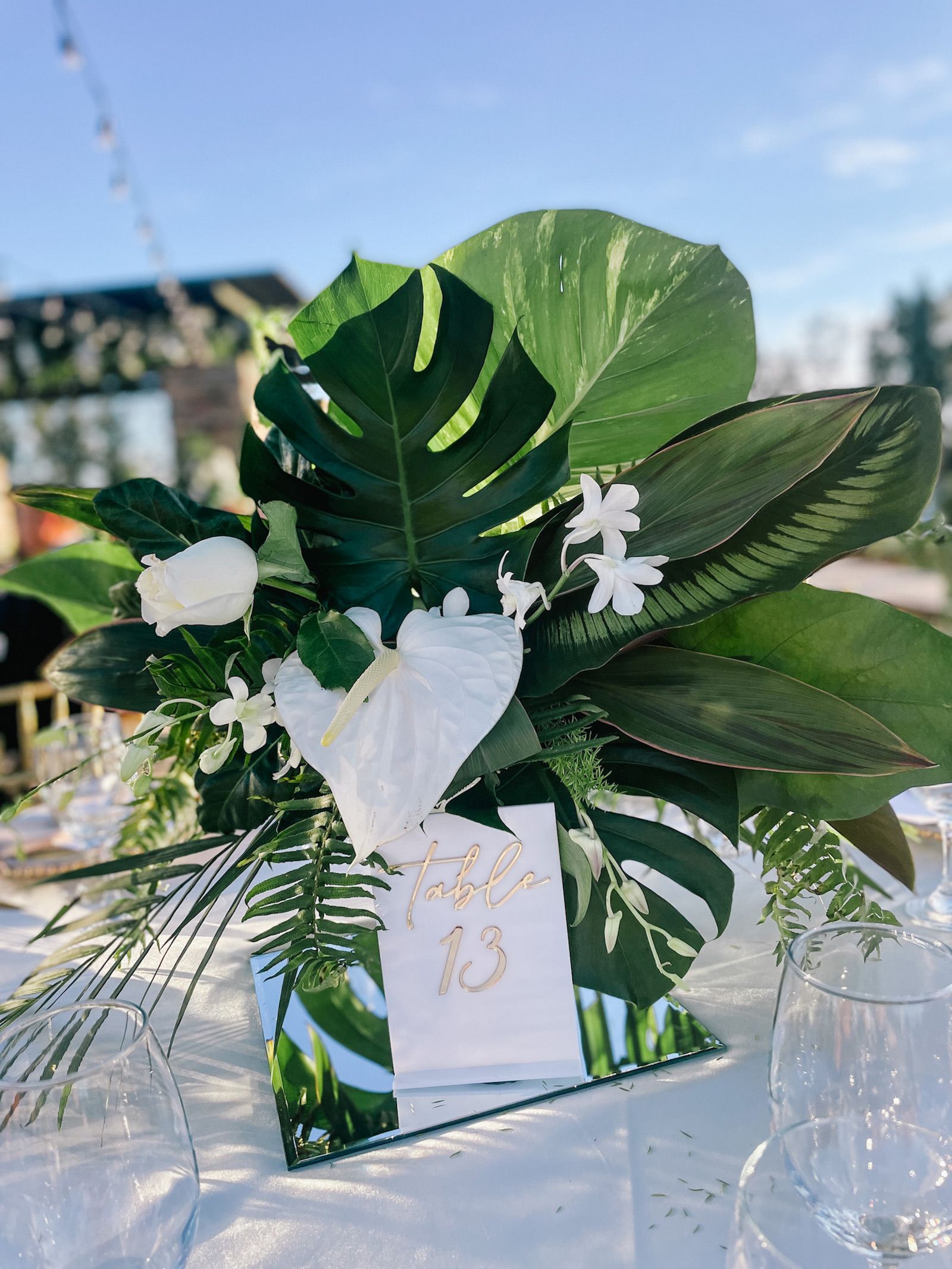 a table number 13 is surrounded by tropical leaves and flowers