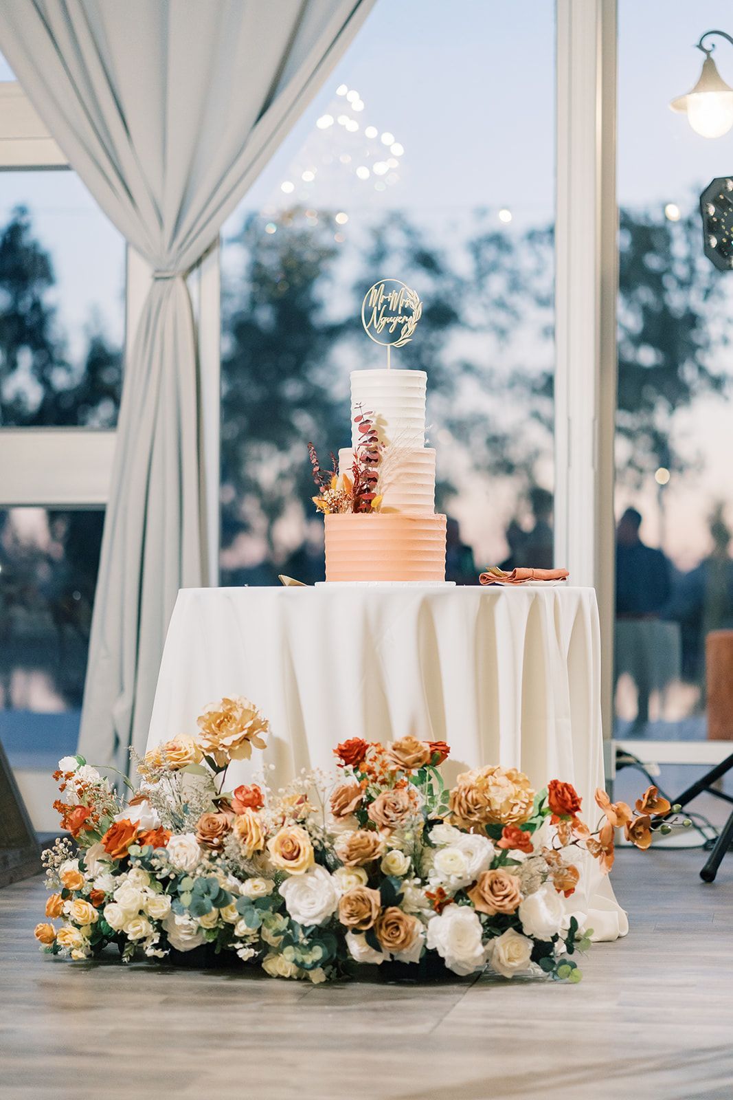 a wedding cake on a table with flowers and a topper that says mr. and mrs.
