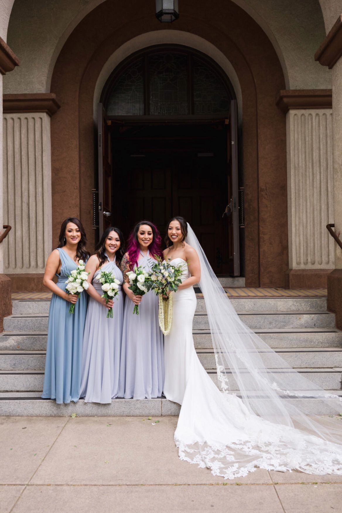 a bride and her bridesmaids pose in front of a church