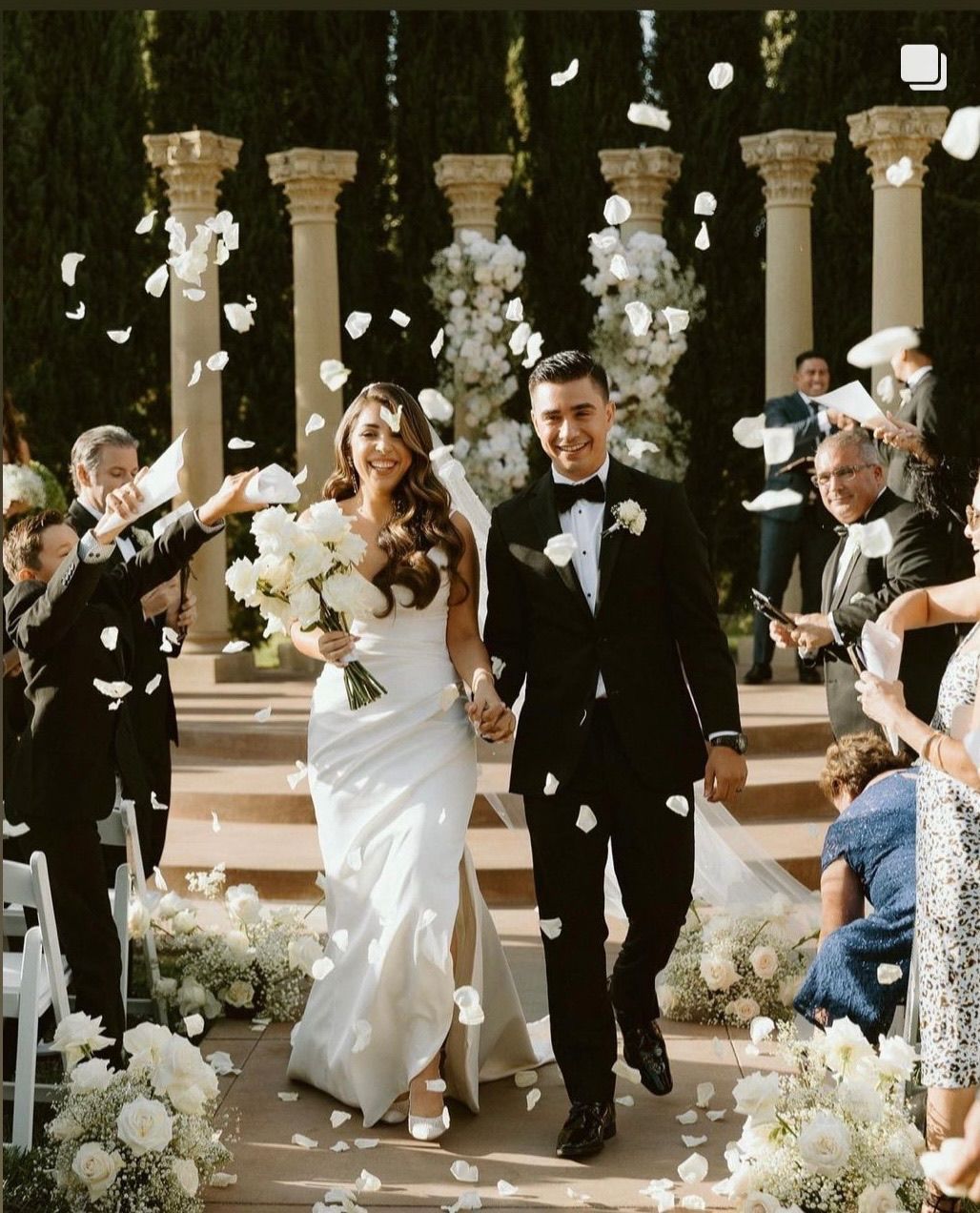 a bride and groom are walking down the aisle with petals being thrown at them