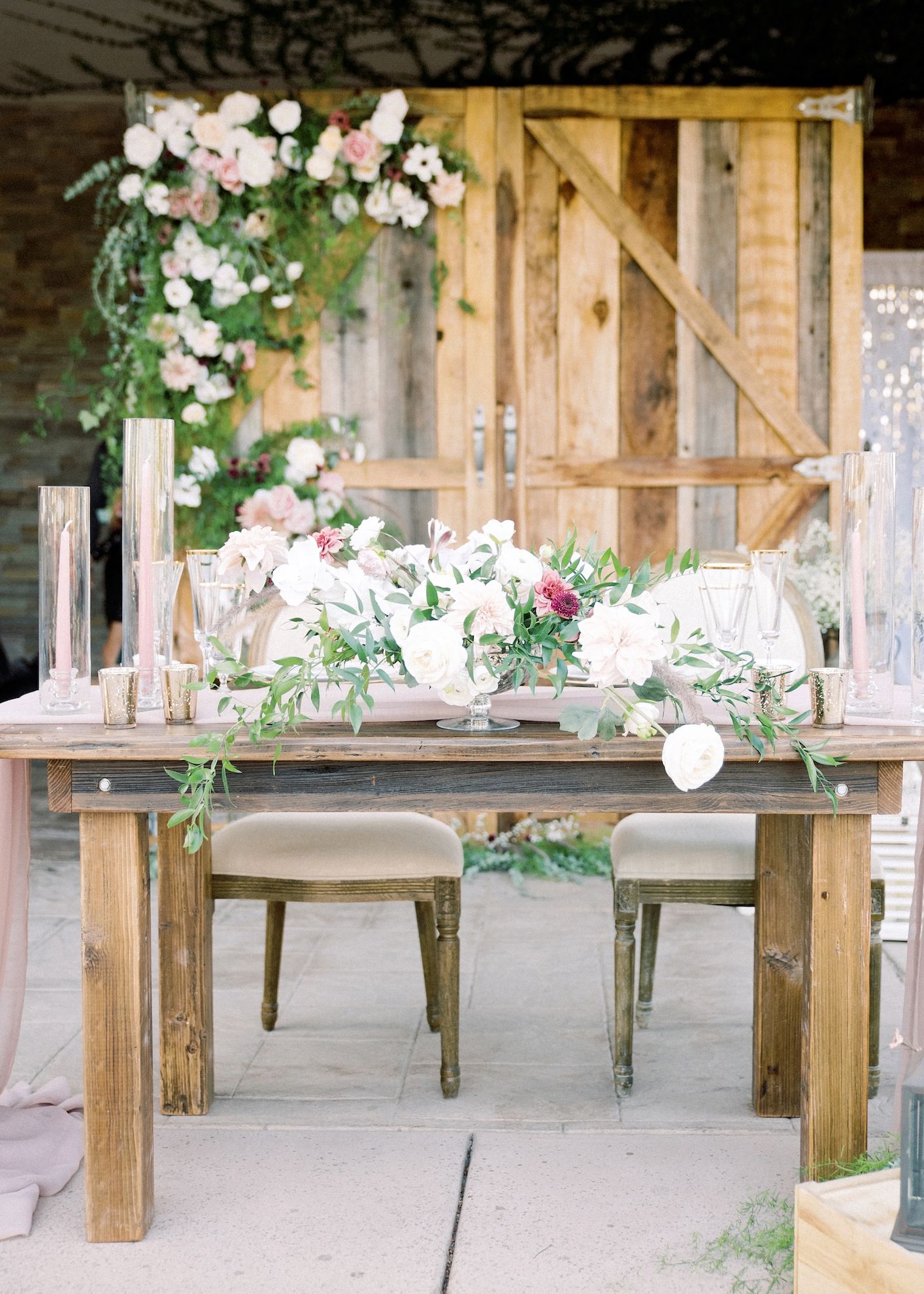 A wooden table with flowers on it is sitting in front of a wooden door.