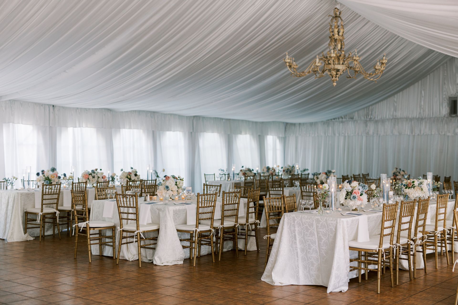 A large tent with tables and chairs set up for a wedding reception.