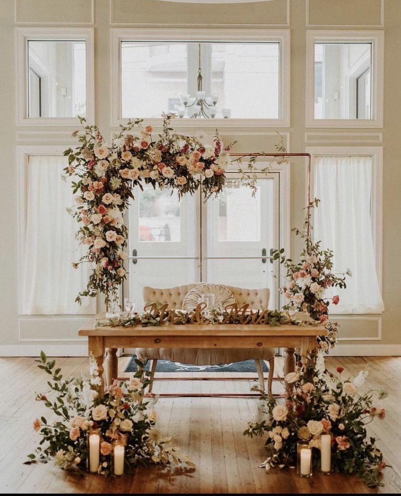 A table with flowers and candles on it in front of a window.