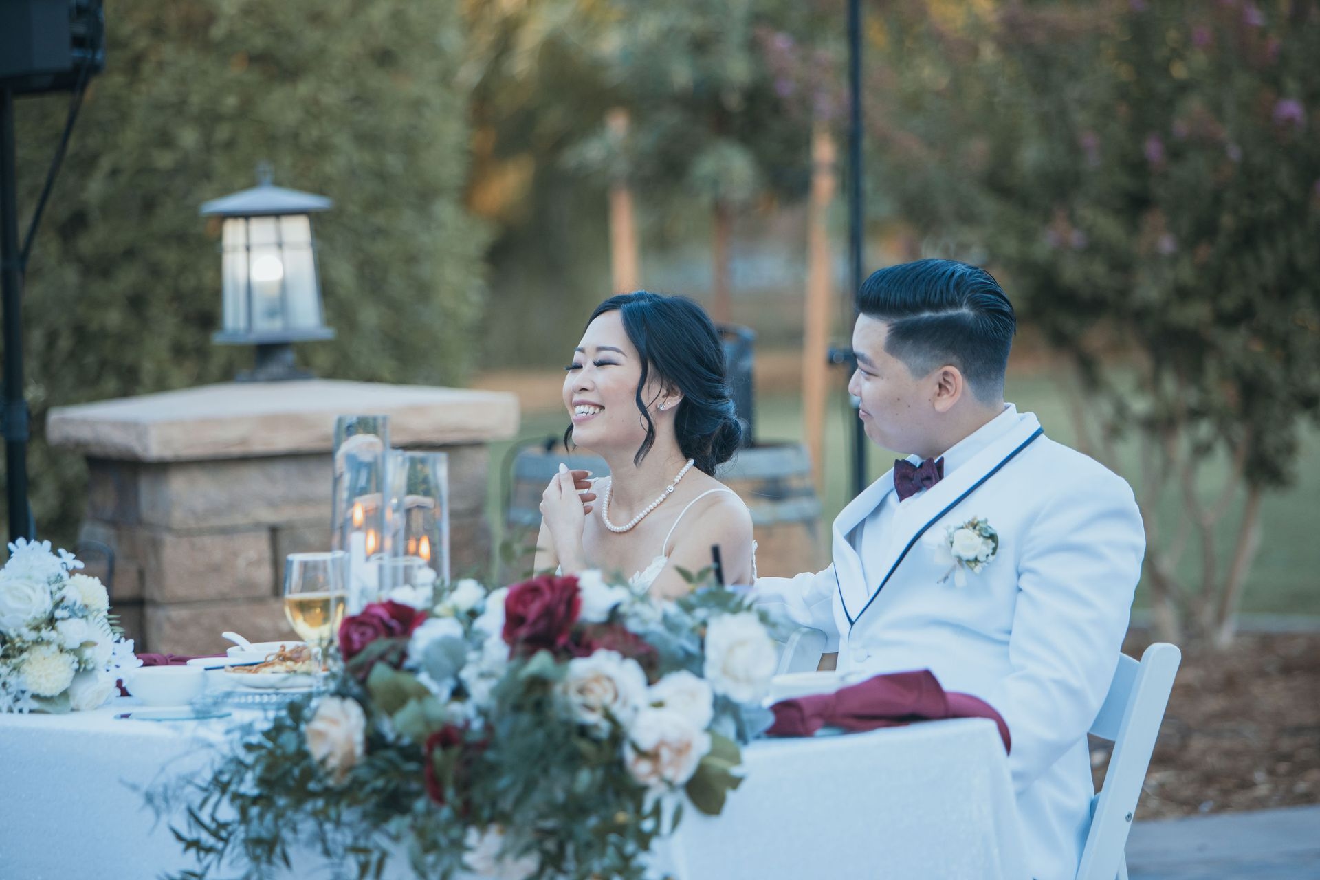 Bride and Groom Sitting at a Table with Floral Arrangements