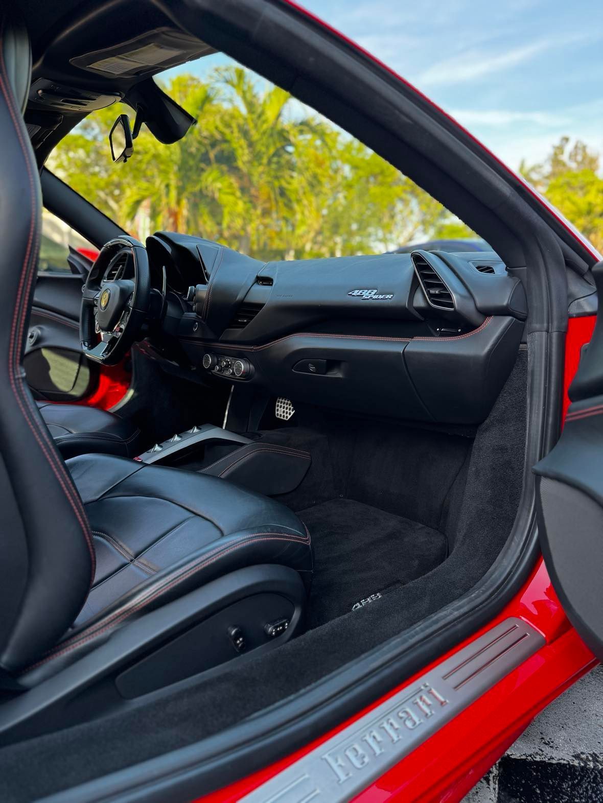 The interior of a red ferrari sports car with the door open.