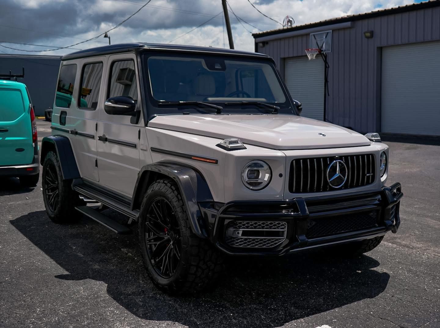 A white mercedes benz g63 amg is parked in a parking lot.