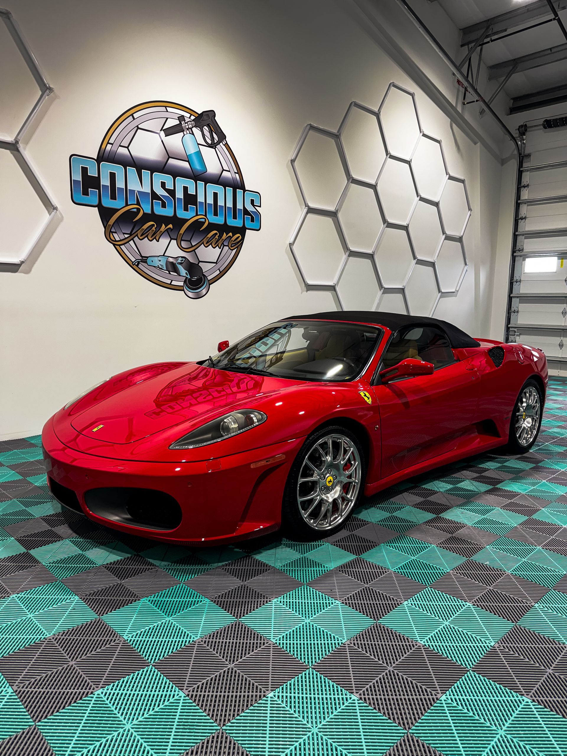 Red sports car in a showroom with a teal and gray patterned floor and hexagon wall decor