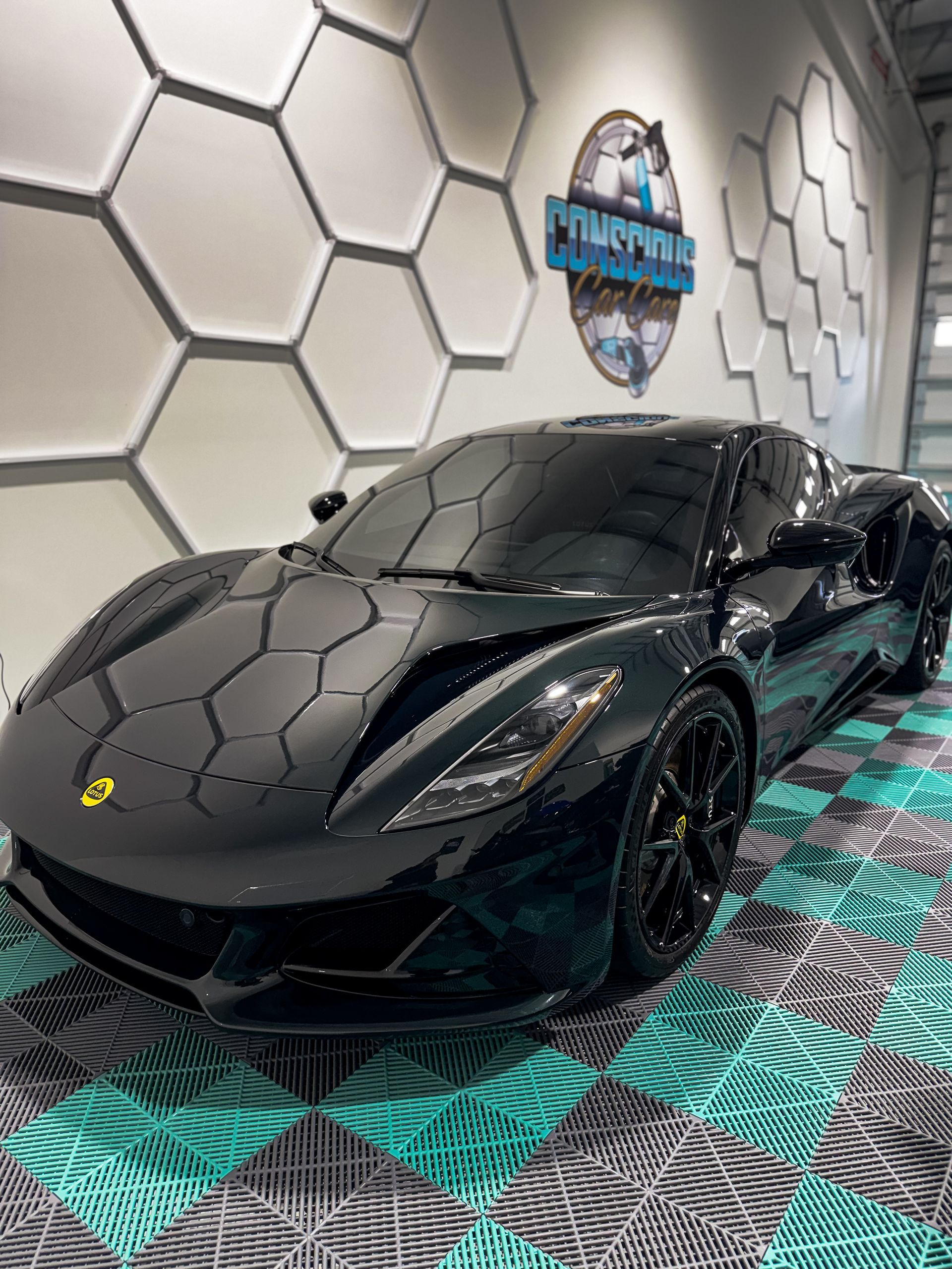 Black Ferrari sports car in a showroom with hexagon wall decor and patterned floor panels