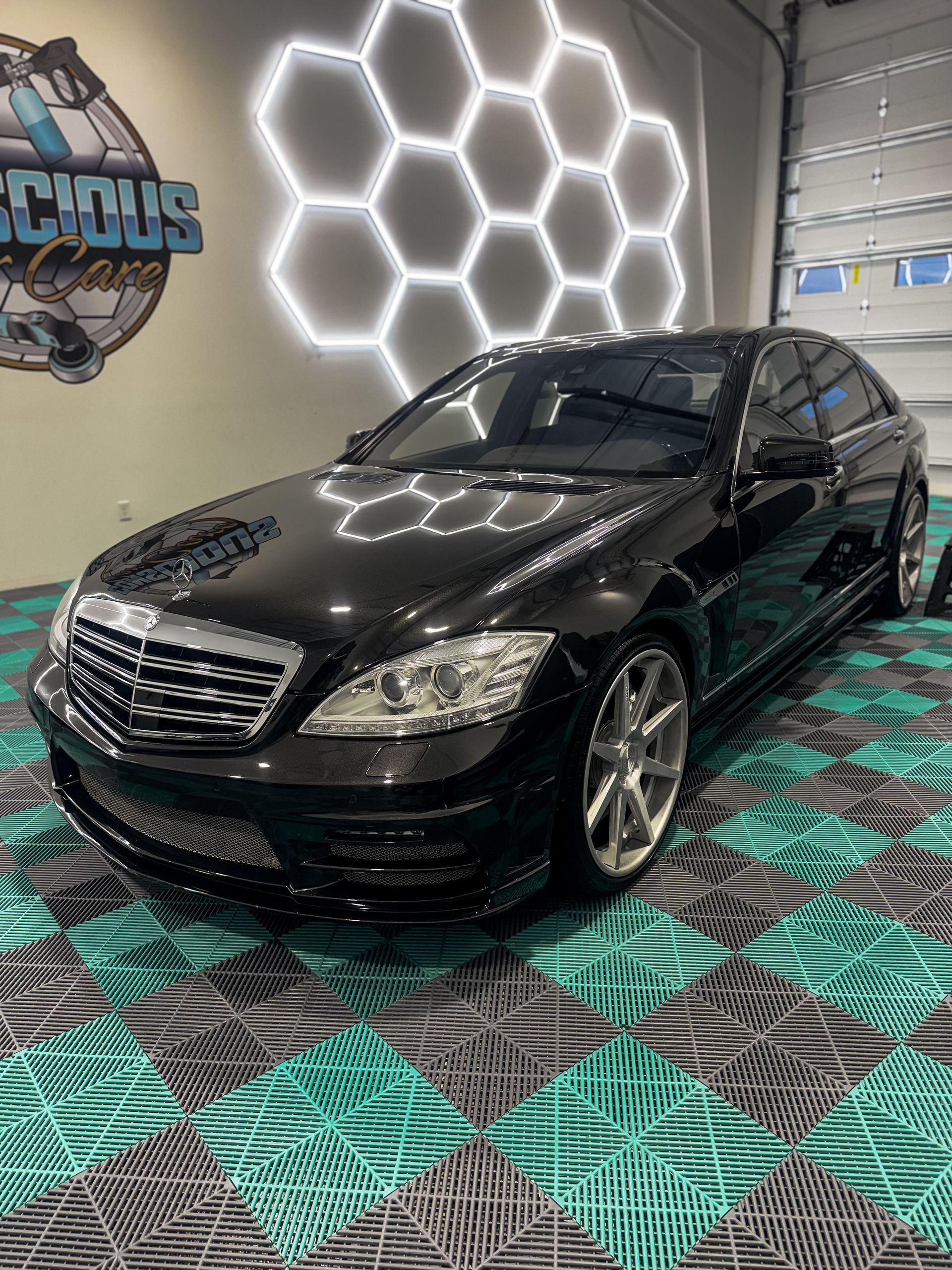 Black Mercedes sedan in a showroom with hexagonal LED wall lights and patterned floor