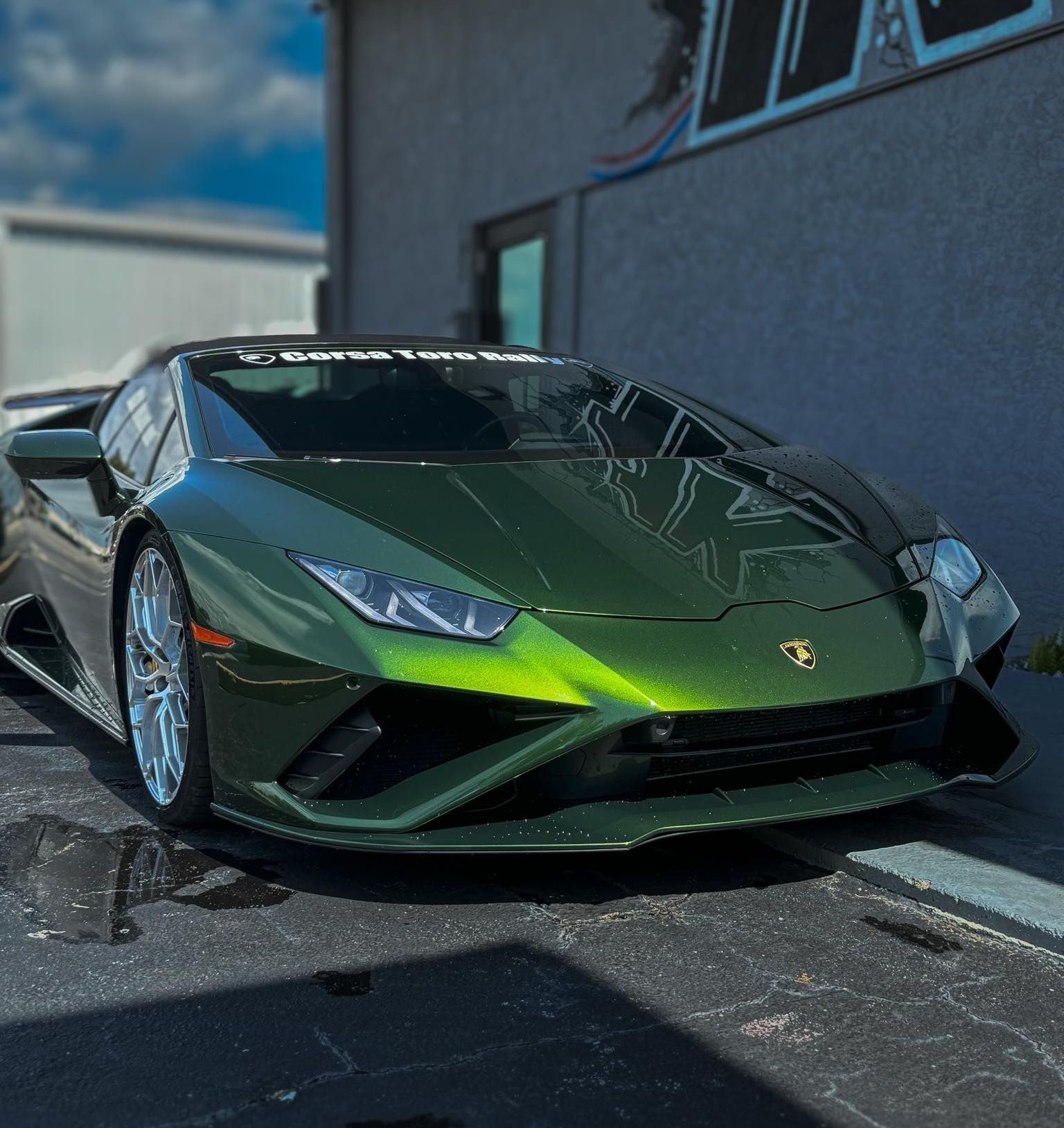 A green lamborghini huracan is parked in front of a building.