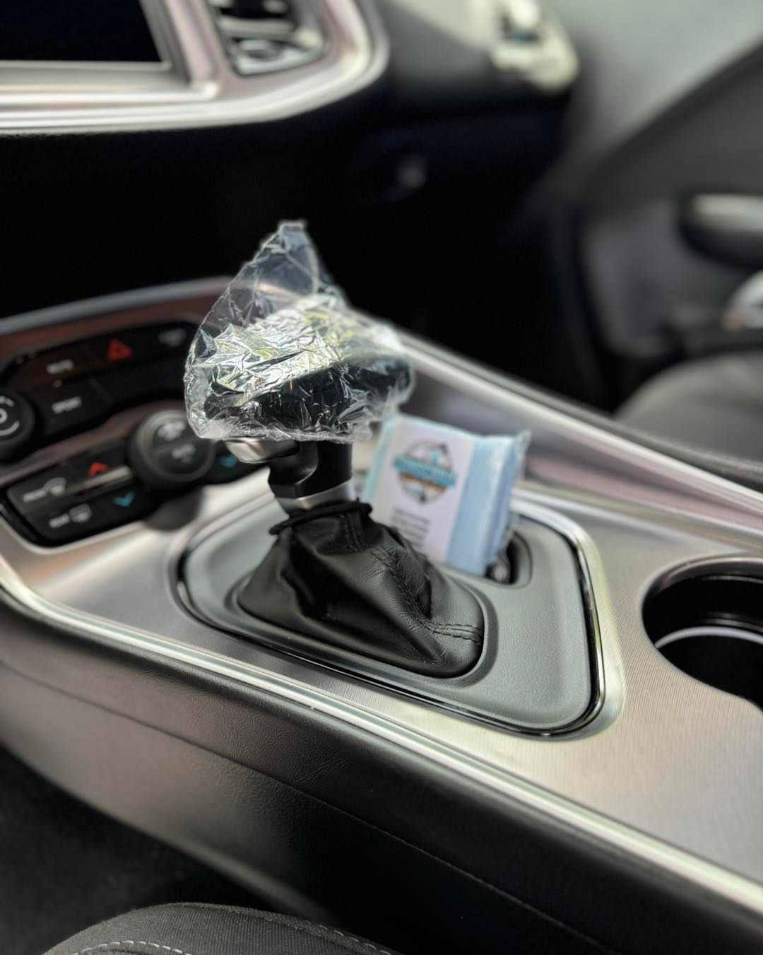 The shifter knob of a dodge challenger is wrapped in plastic.