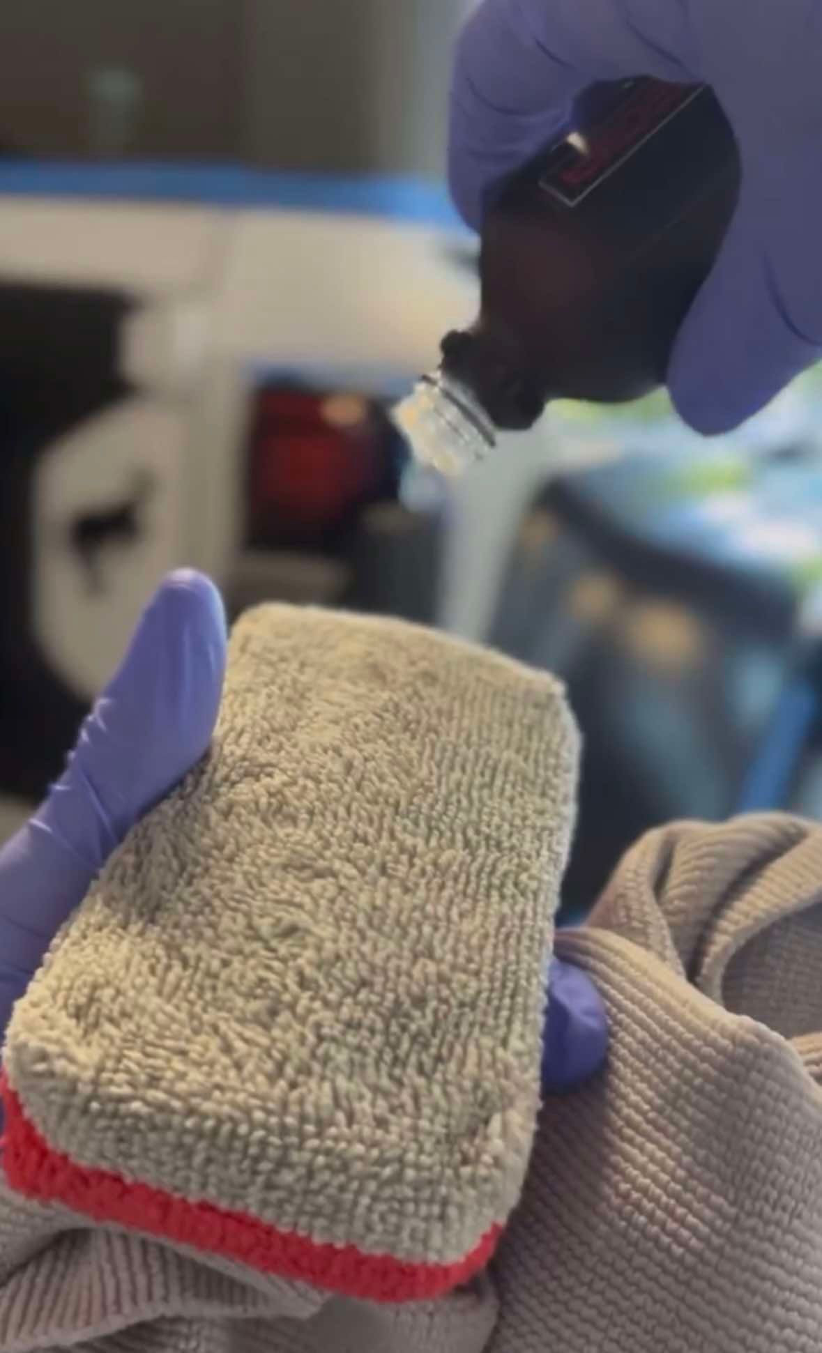 A person is applying ceramic coating to a blue car.