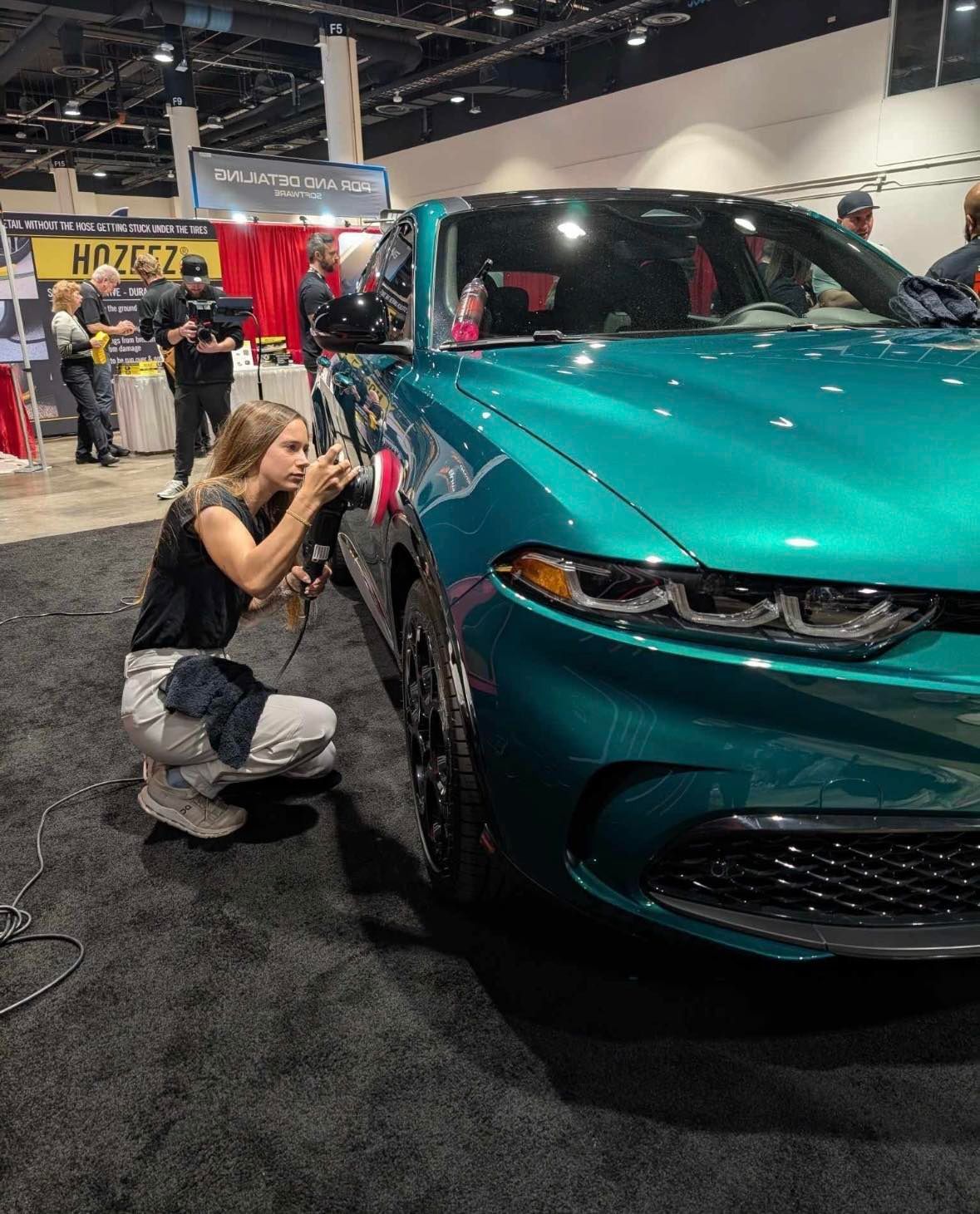 A person is polishing the hood of a car with a machine.