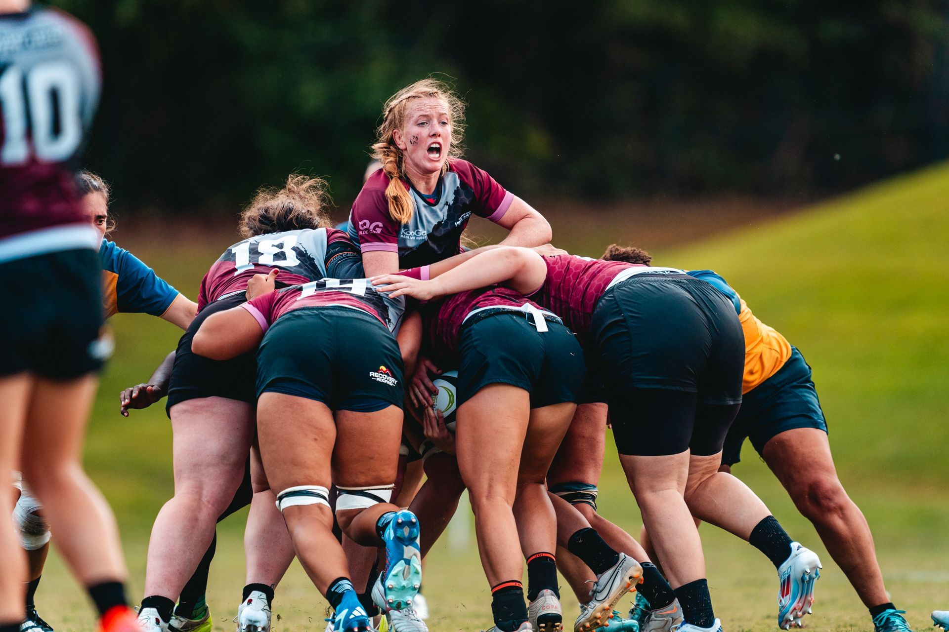 A group of women are playing rugby on a field.