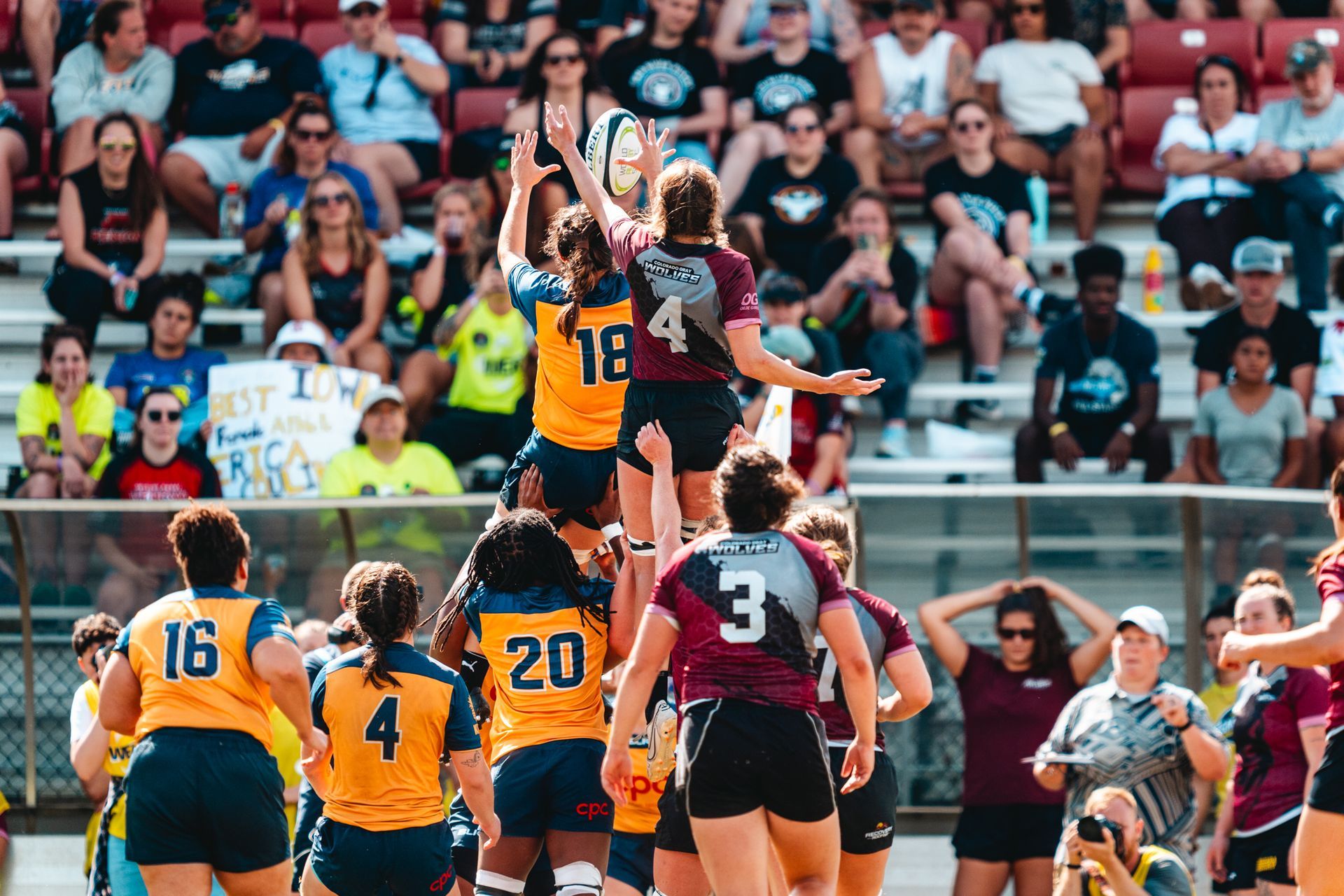 A group of women are playing rugby in front of a crowd.