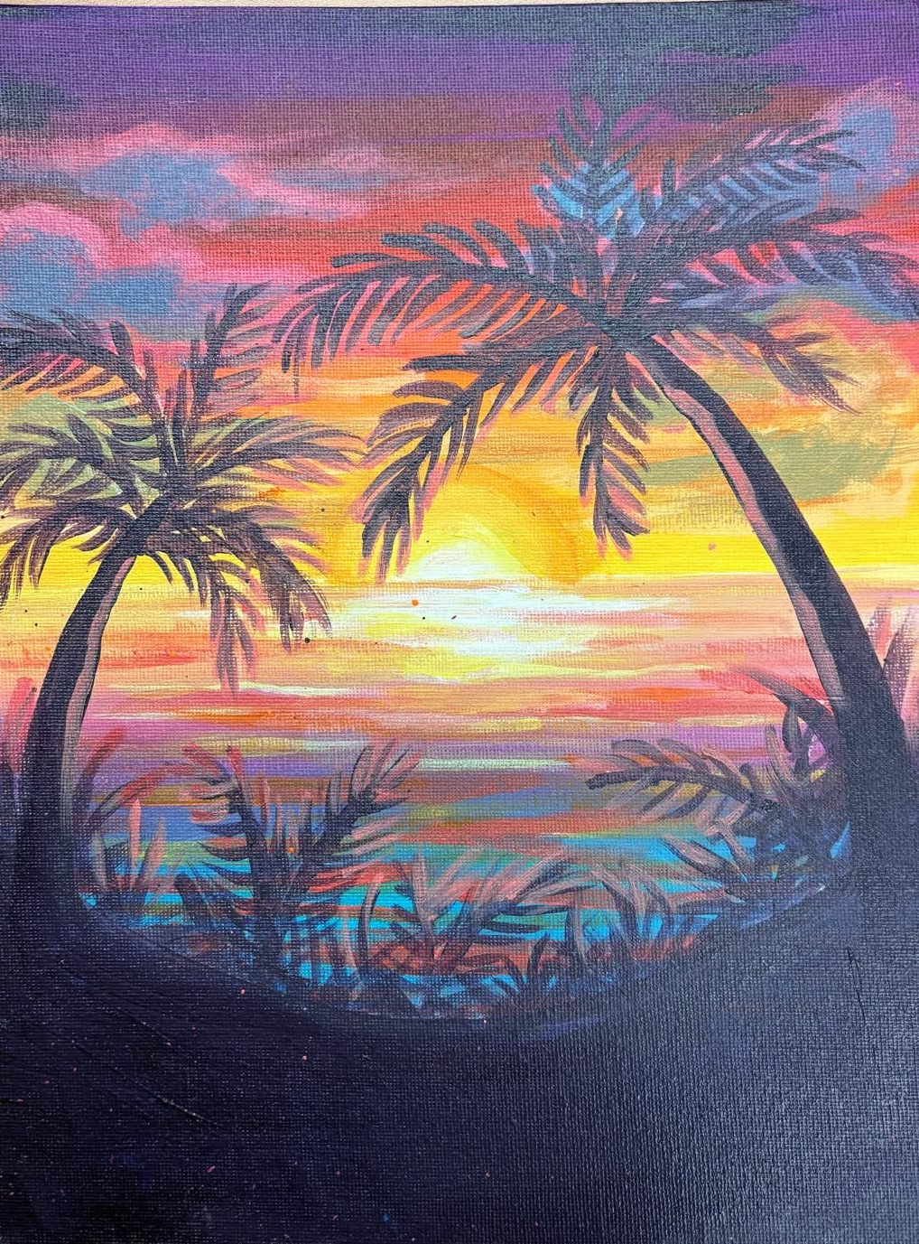 Sunset with palm trees silhouetted against a colorful sky over the ocean.