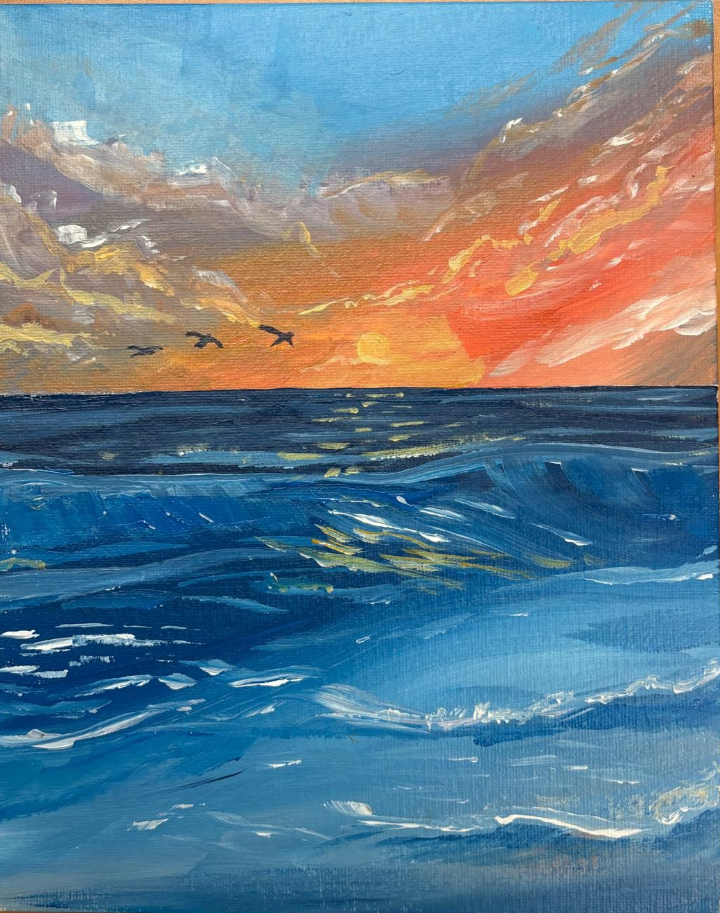 Sunset over ocean with birds flying; orange, blue, and white hues.