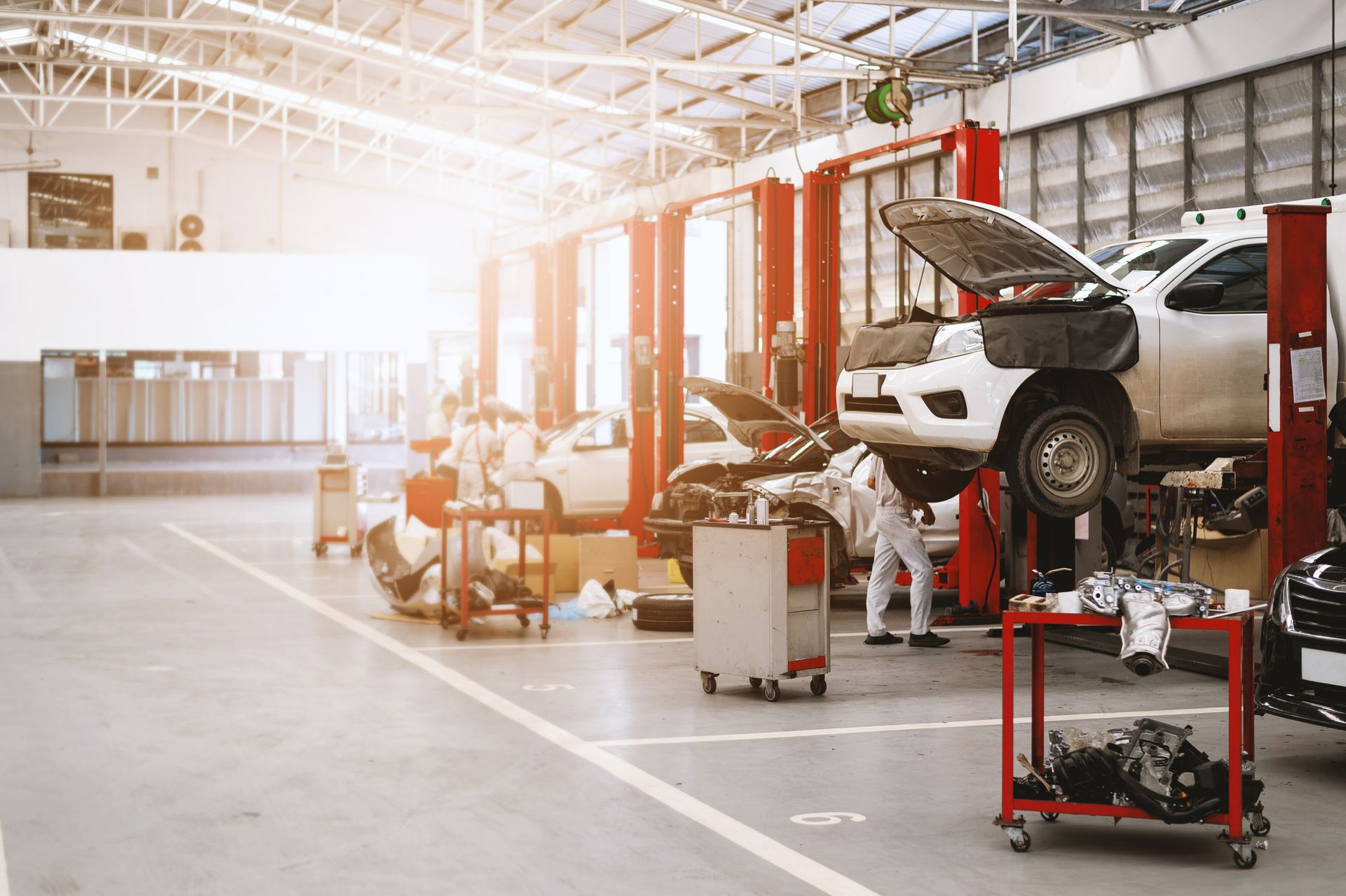 Auto repair shop with a car on a lift, mechanics working, and tools under bright industrial lights
