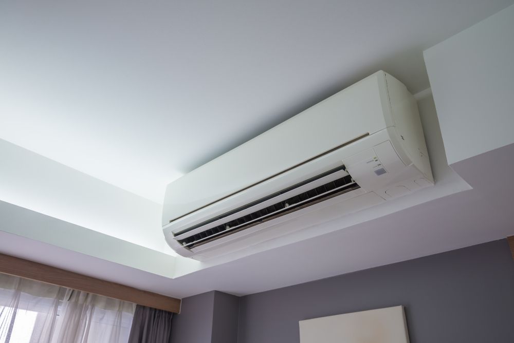 White wall-mounted air conditioner on a light gray ceiling in a modern room - TropicAir Electrical in Townsville