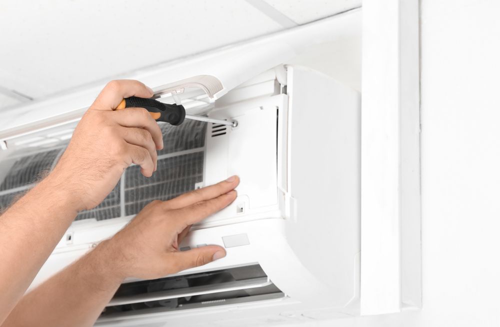 Male Technician Fixing Modern Air Conditioner Indoors — Replace Your Home’s Air Conditioner in Townsville, QLD
