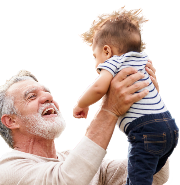 A smiling person with gray hair and a beard lifts a baby in a striped shirt high into the air against a white background.