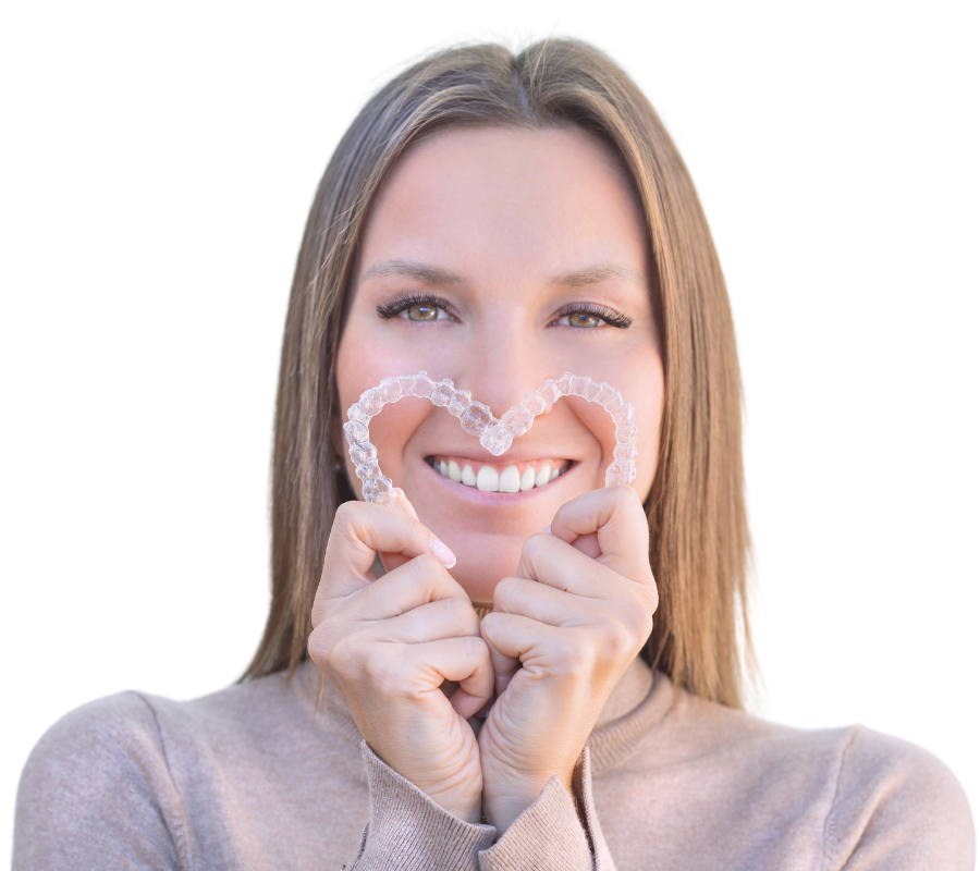 Women holding clear aligners in the shape of a heart over top of her mouth and teeth.