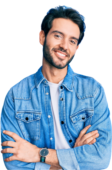 A man in a denim shirt is smiling with his arms crossed.