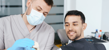 A dentist is explaing custom fitted mouth guards in a dental office.