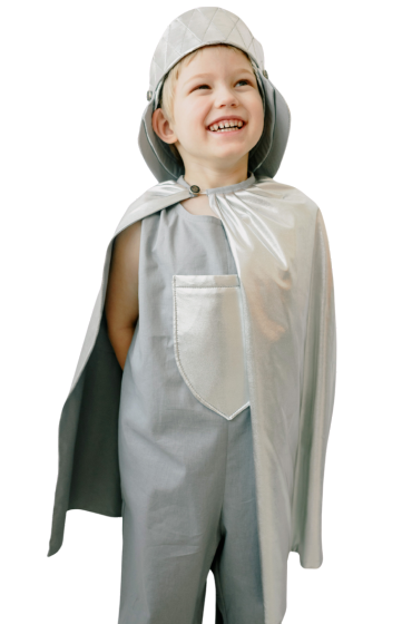 A little boy wearing a cape and hat is smiling.