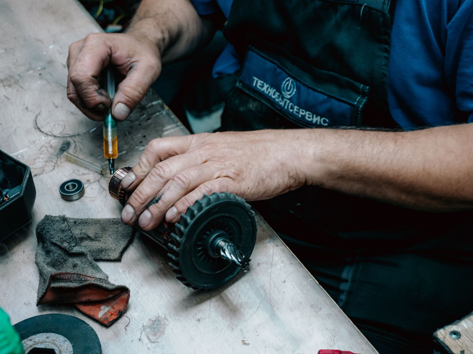 Mechanic’s hands using a screwdriver to repair a small motor on a workbench, with tools nearby