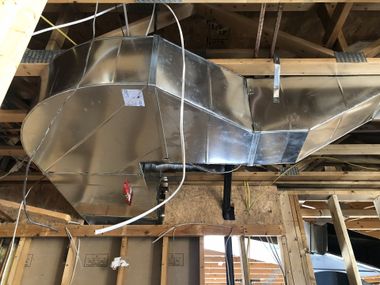 Galvanized metal HVAC ductwork installed in unfinished ceiling.