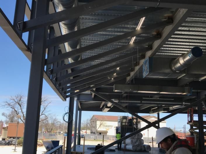 Metal rooftop canopy under construction with workers and scaffolding at an outdoor site