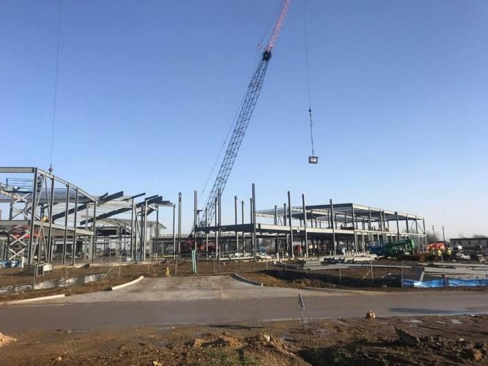 Construction site with steel frame buildings and a crane under a clear blue sky.