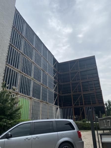 Modern building with vertical slats beside a silver minivan under a cloudy sky