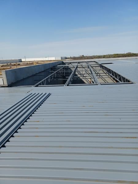 Rooftop construction with metal framing and skylights under a clear blue sky