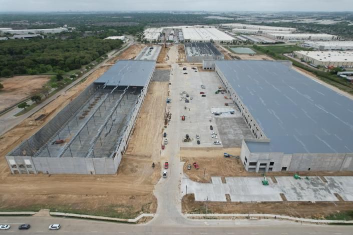 Aerial view of a large industrial construction site with warehouses and dirt roads