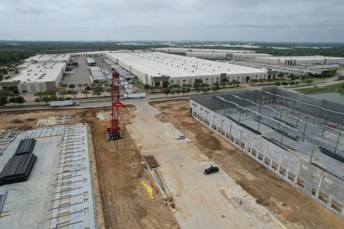 Aerial view of a large construction site with cranes, dirt roads, and industrial buildings under development