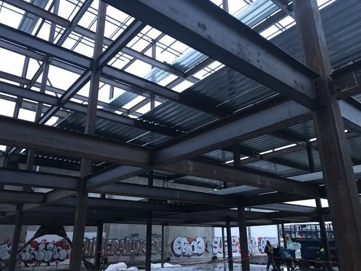 Abandoned warehouse interior with steel beams, skylights, and graffiti-covered walls