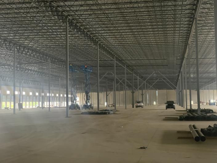 Empty warehouse interior with steel columns and stacked materials on the floor