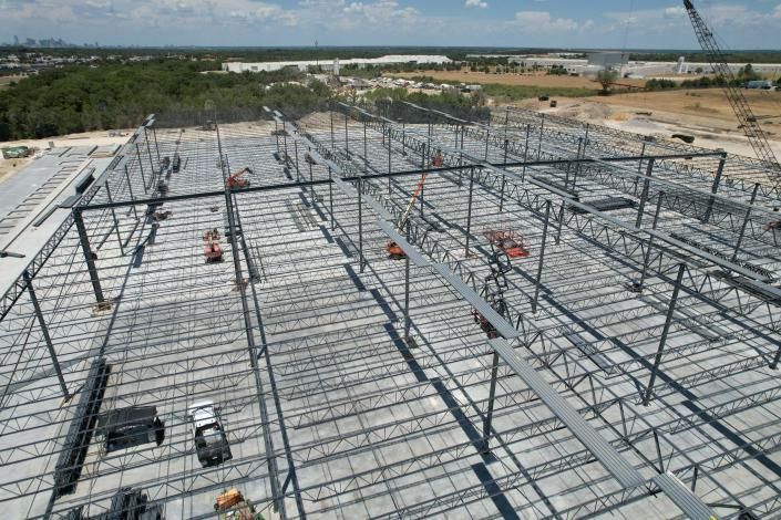 Steel framework under construction with workers on a large building site under a clear sky