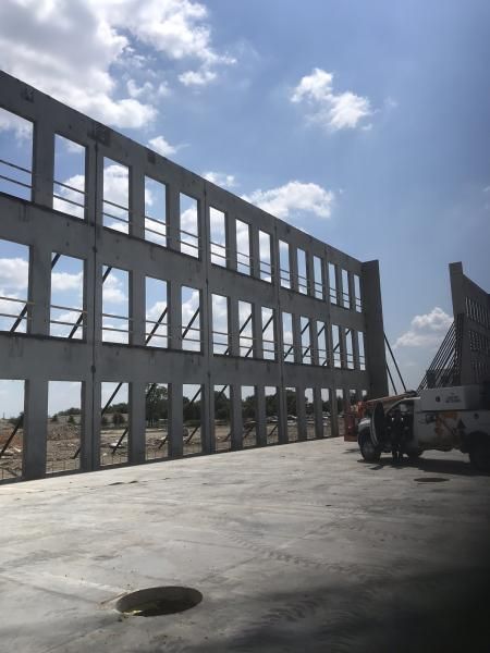 Concrete building frame under construction beside a truck on a sunny day