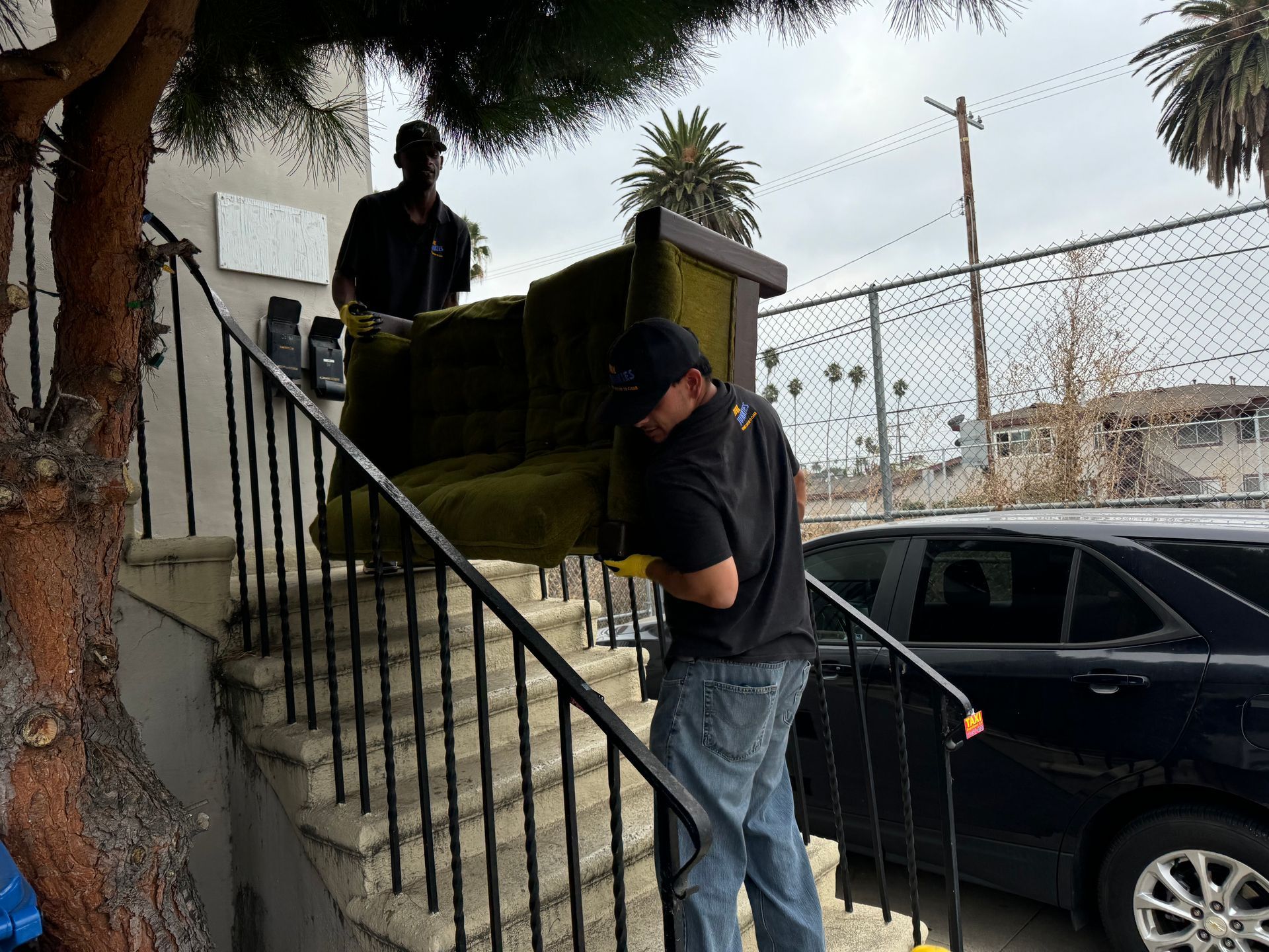 Two workers removing a couch down a stair set.